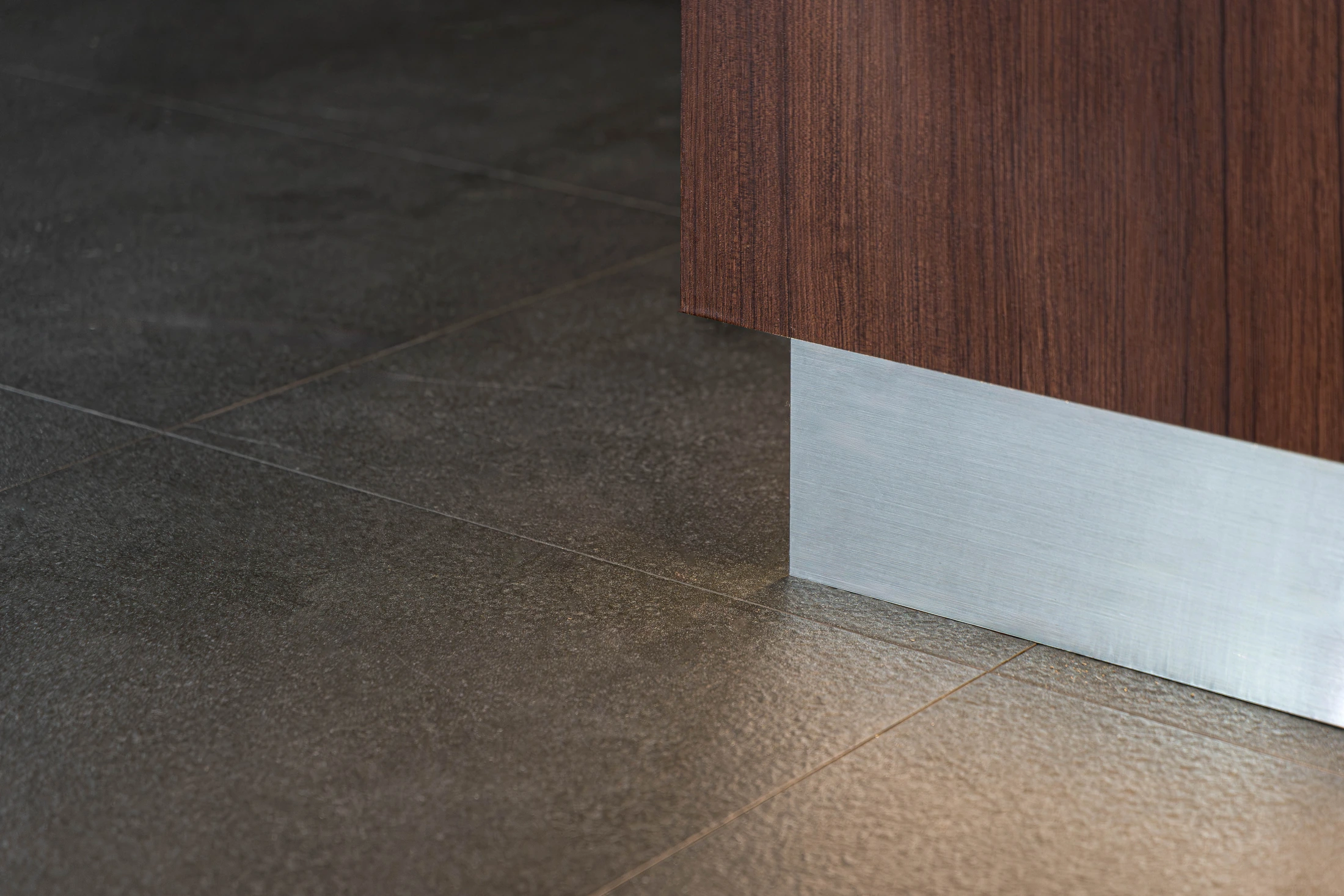 Timber counter, stainless-steel plinth and floor junction